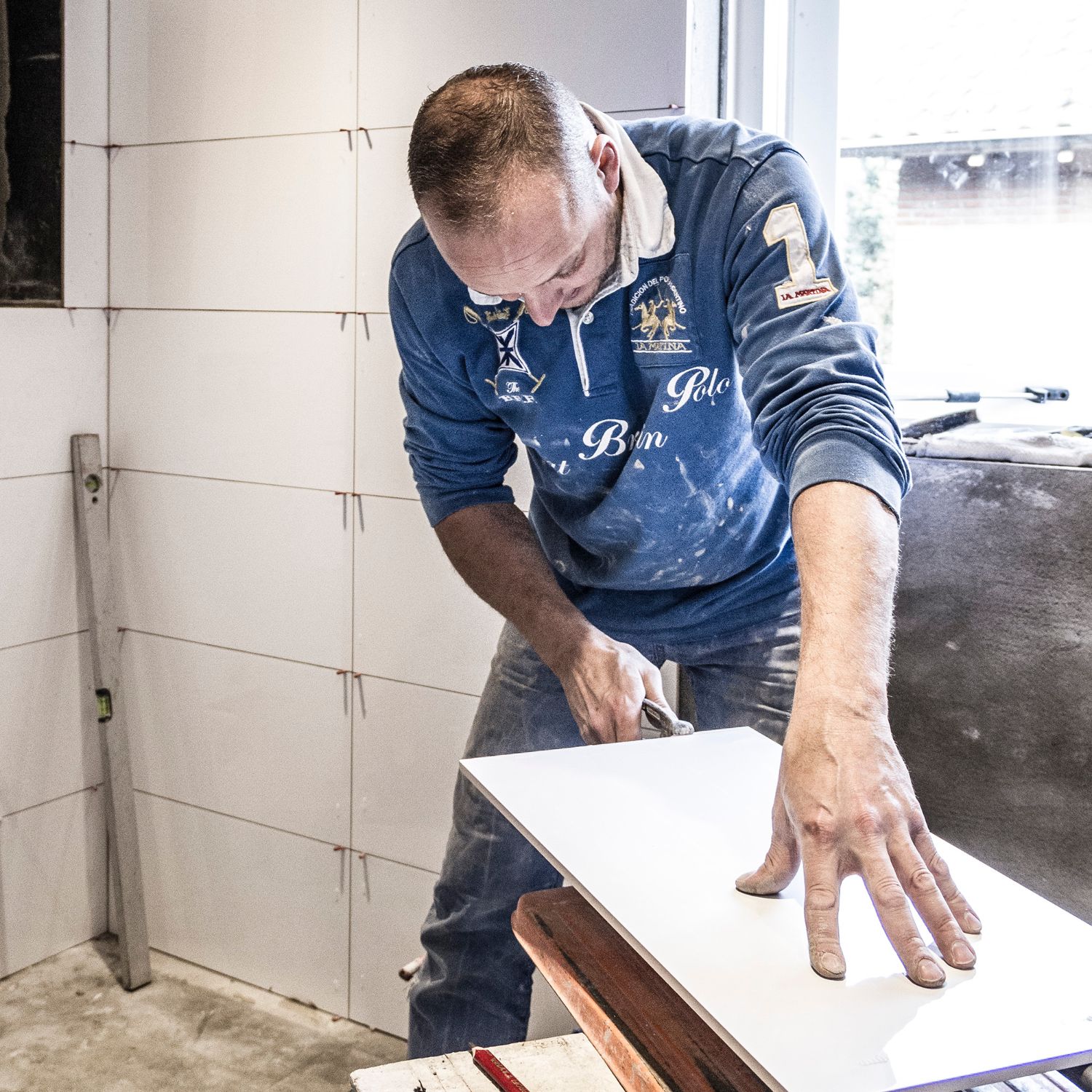 Alex van den Berg snijdt een grote wandtegel op maat