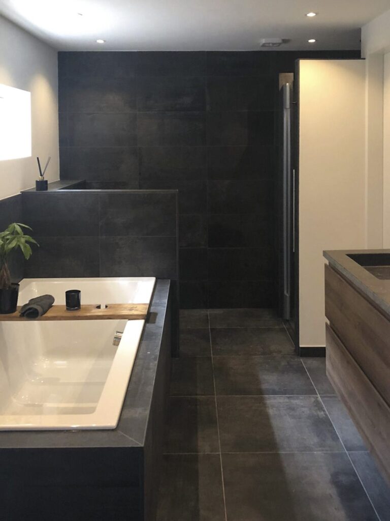Badkamer met antraciet tegels, ligbad en inloopdouche